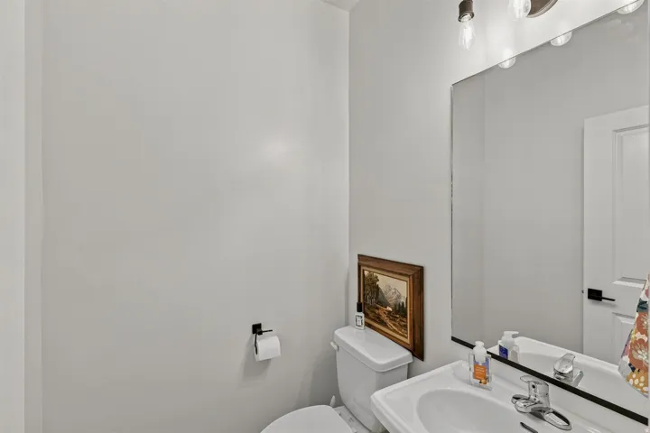 Pedestal sink with chrome faucet, large wall mirror, and modern vanity lighting