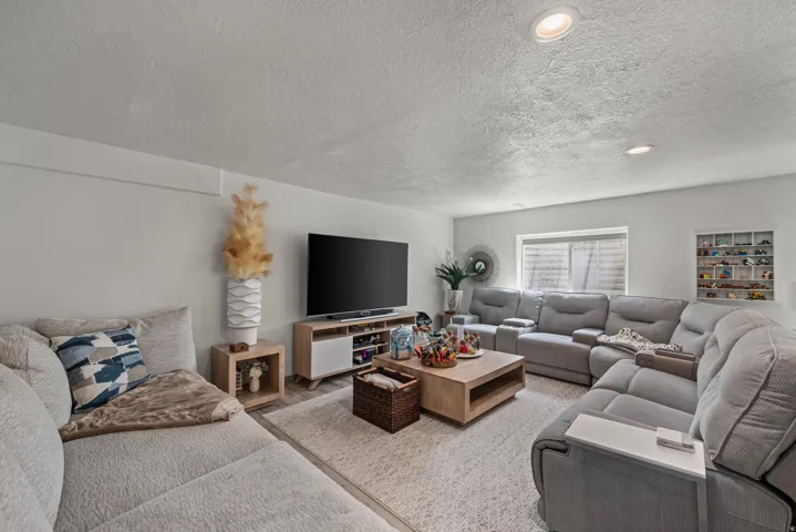 Recessed lighting, wood-finish media console, integrated shelving, window with blinds, and light-toned walls