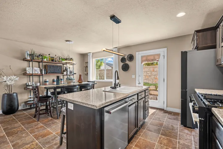 Kitchen featuring a central island with granite countertop, integrated dishwasher, and stainless steel sink