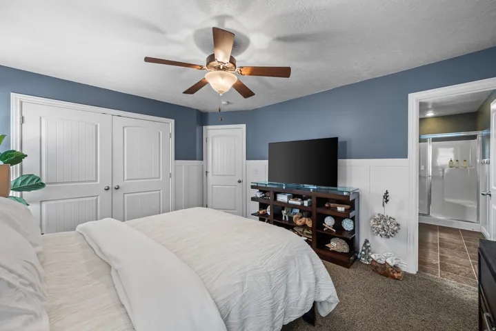 Room featuring wainscoting, a ceiling fan, and carpeted flooring