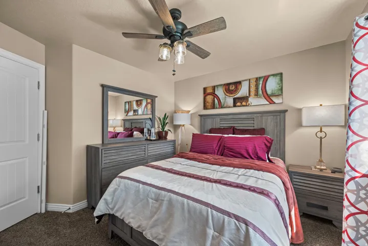 Carpeted room featuring a ceiling fan with light kit, textured walls, and a white paneled door