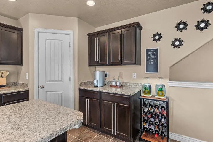 Dark wood cabinetry, speckled countertops, recessed lighting, and a white paneled door