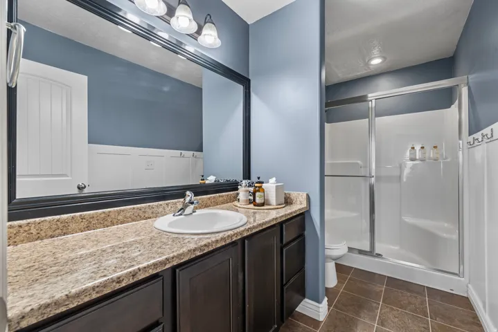 Bathroom vanity with an integrated sink, broad mirror, and a shower with sliding glass doors