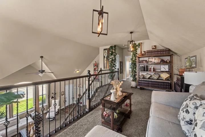 Carpeted loft area featuring a wrought iron railing, vaulted ceiling, and recessed lighting