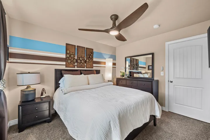 Ceiling fan with integrated lighting, wood-finish flooring, white paneled door, built-in mirror, and wall-mounted art