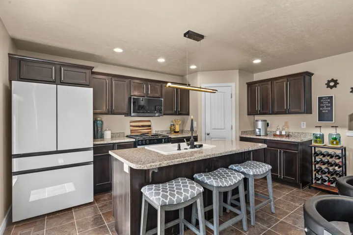 Kitchen featuring dark wood-finish cabinetry, light-toned countertops, and a center island with integrated sink