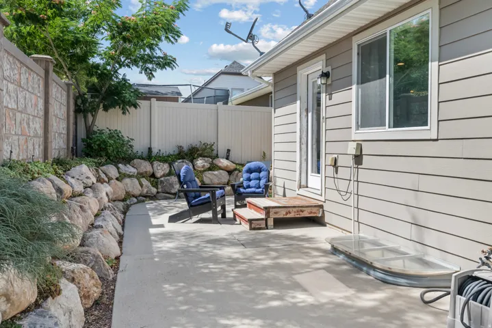 Concrete patio with a rock retaining wall, horizontal siding, and a privacy fence