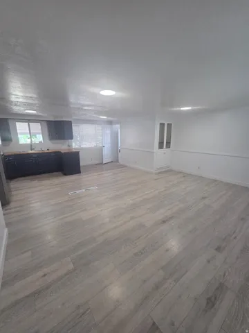 Open-concept living area with wood-finish flooring, recessed lighting, and a built-in display cabinet