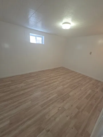 Wood-finish flooring, white paneling, and a flush-mount ceiling light fixture
