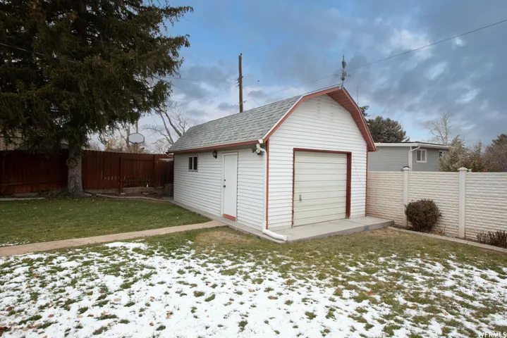 Detached white-sided garage with a gambrel roof and a single garage door