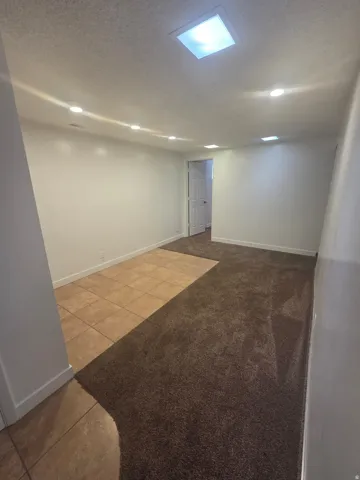 Recessed ceiling lighting, distinct flooring areas, and a square ceiling light fixture