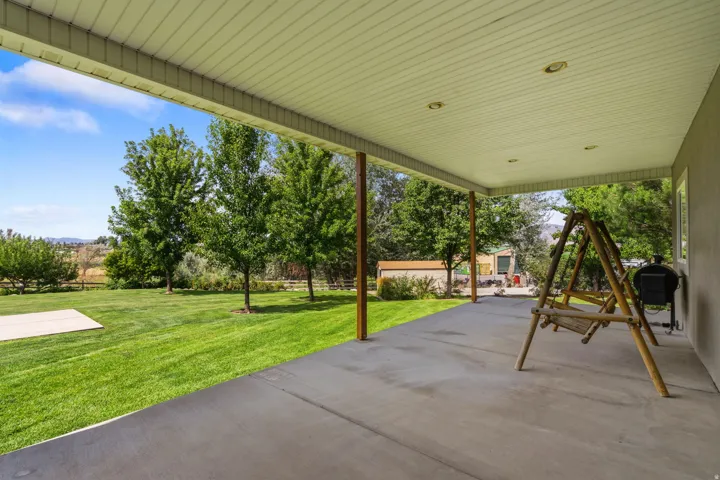 Expansive covered patio with recessed lighting, concrete flooring, and support columns