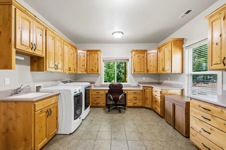 Extensive wood cabinetry, expansive countertop space, integrated utility sink, tile flooring, and multiple windows