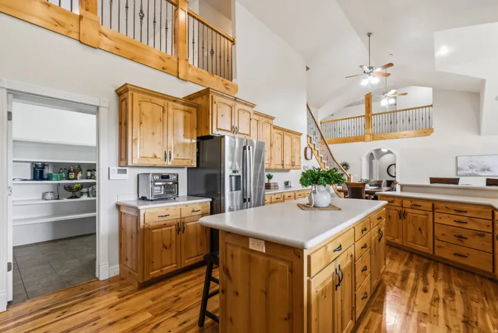 Open-concept kitchen featuring wood-finish flooring, light wood cabinetry, white countertops, and a center island