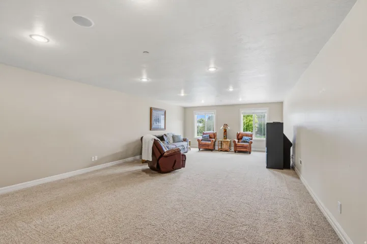 Spacious room featuring neutral carpeting, recessed lighting, and multiple windows with white trim