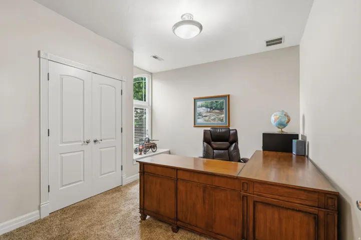 Double-door entry, tall window with blinds, overhead light fixture, light-toned walls, and carpet flooring