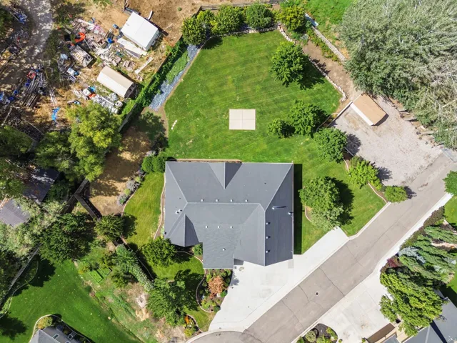 Expansive property featuring a grey shingle roof, paved driveway, mature trees, and a manicured lawn
