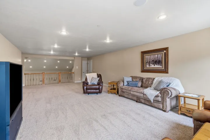 Spacious carpeted room with recessed lighting and a wood banister
