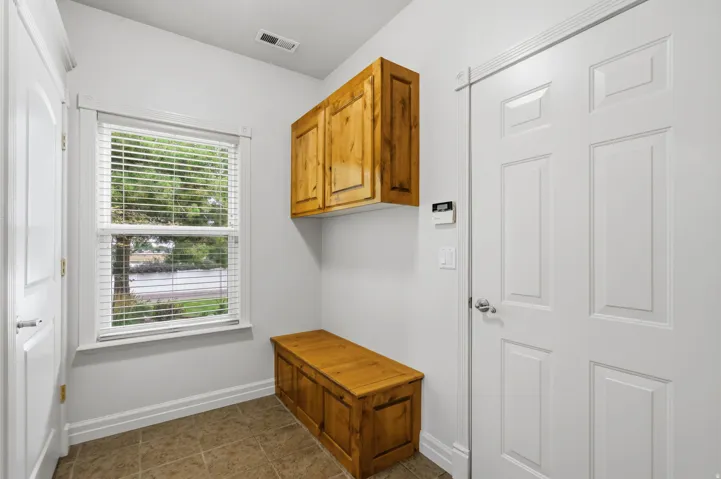 Built-in wood cabinetry, a coordinating wood storage bench, and durable tile flooring