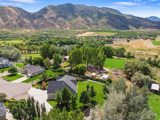Expansive property with a dark shingle roof, surrounded by mature trees and manicured lawns