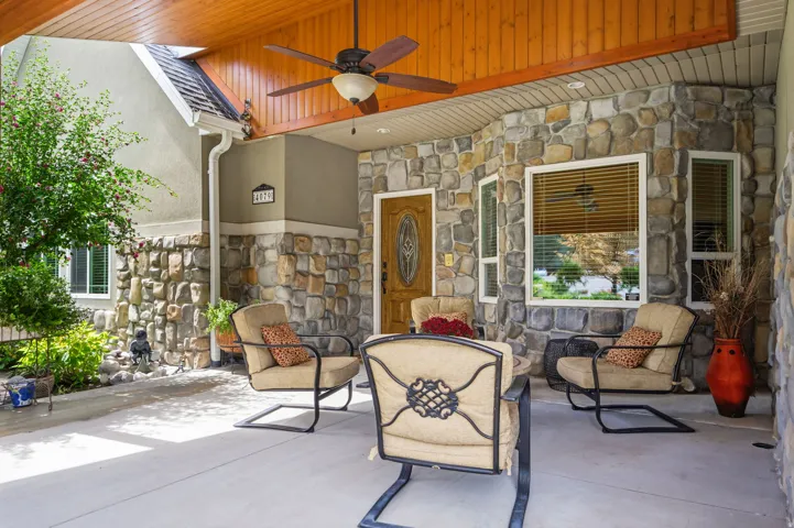 Covered porch with stone veneer siding, wood-finish ceiling, and ceiling fan
