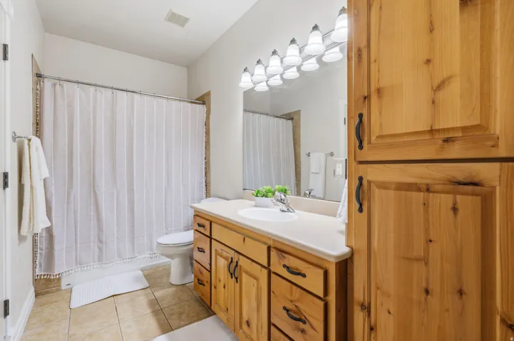 Bathroom featuring a single vanity with wood cabinetry, a built-in linen cabinet, tile flooring, and a shower-tub combination
