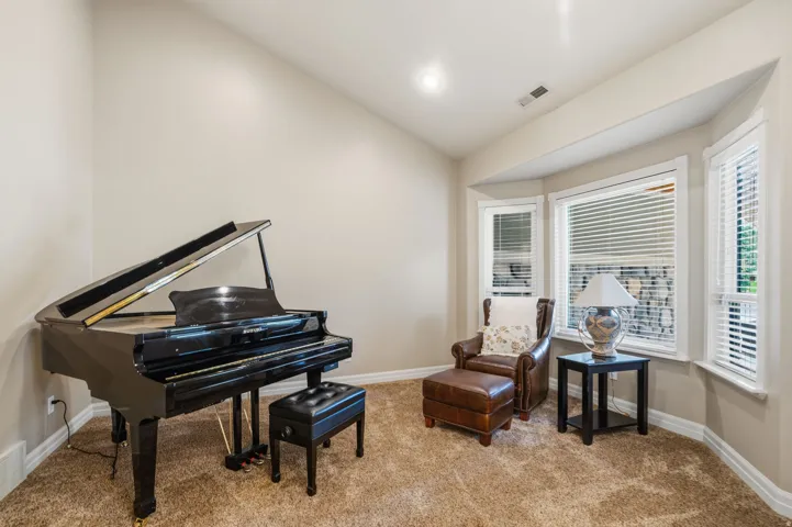 Recessed lighting illuminates this carpeted room featuring a bay window with white blinds and trim