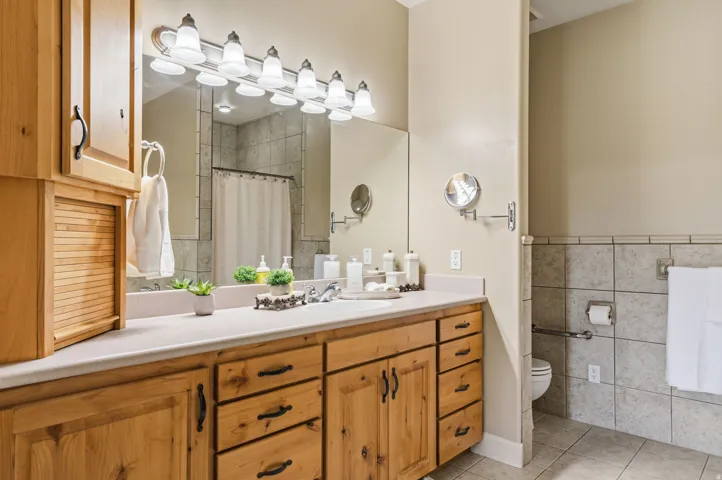 Extended vanity with ample storage, a large mirror, and a multi-bulb light fixture