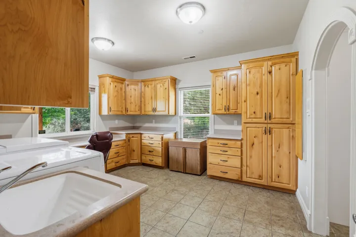 Extensive wood cabinetry, durable tile flooring, recessed ceiling lighting, a deep utility sink, and a built-in folding counter