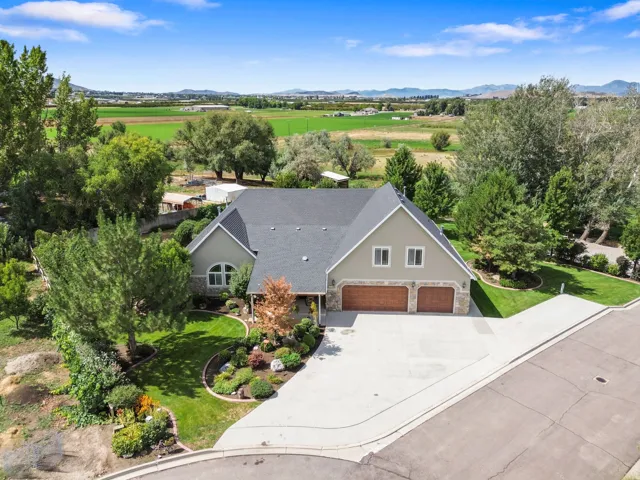 Expansive front lawn with mature landscaping, a two-car garage, and a paved driveway