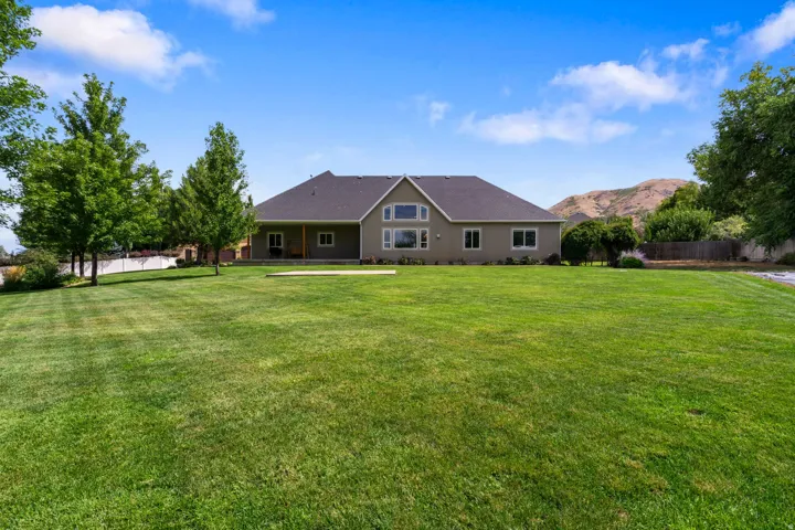 Expansive green lawn with mature trees and a distant mountain backdrop