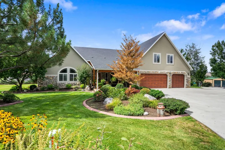 Stucco and stone exterior with arched windows, a covered porch, and two-car garage