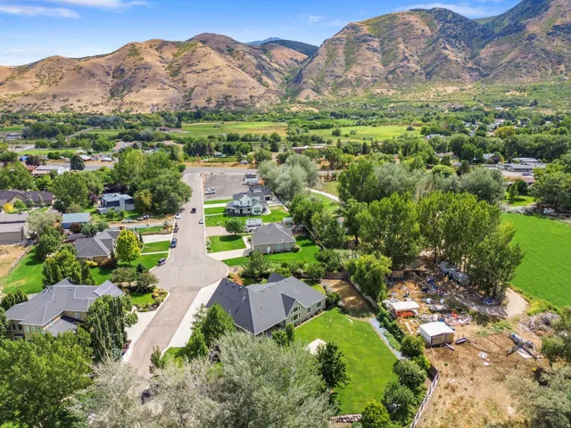 Aerial neighborhood overview featuring a cul-de-sac, mature trees, and mountainous topography