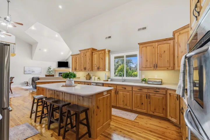 Kitchen featuring a center island, wood-finish flooring, vaulted ceiling, and wood cabinetry with undermount lighting