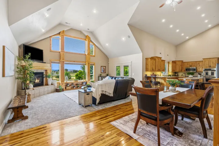 Vaulted ceiling with exposed wood beams, built-in shelving, gas fireplace with tile surround, wood-finish flooring, and recessed lighting