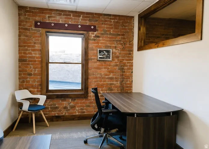 Exposed brick wall with a single window featuring a wood-finish frame, wood-finish flooring, and a drop ceiling