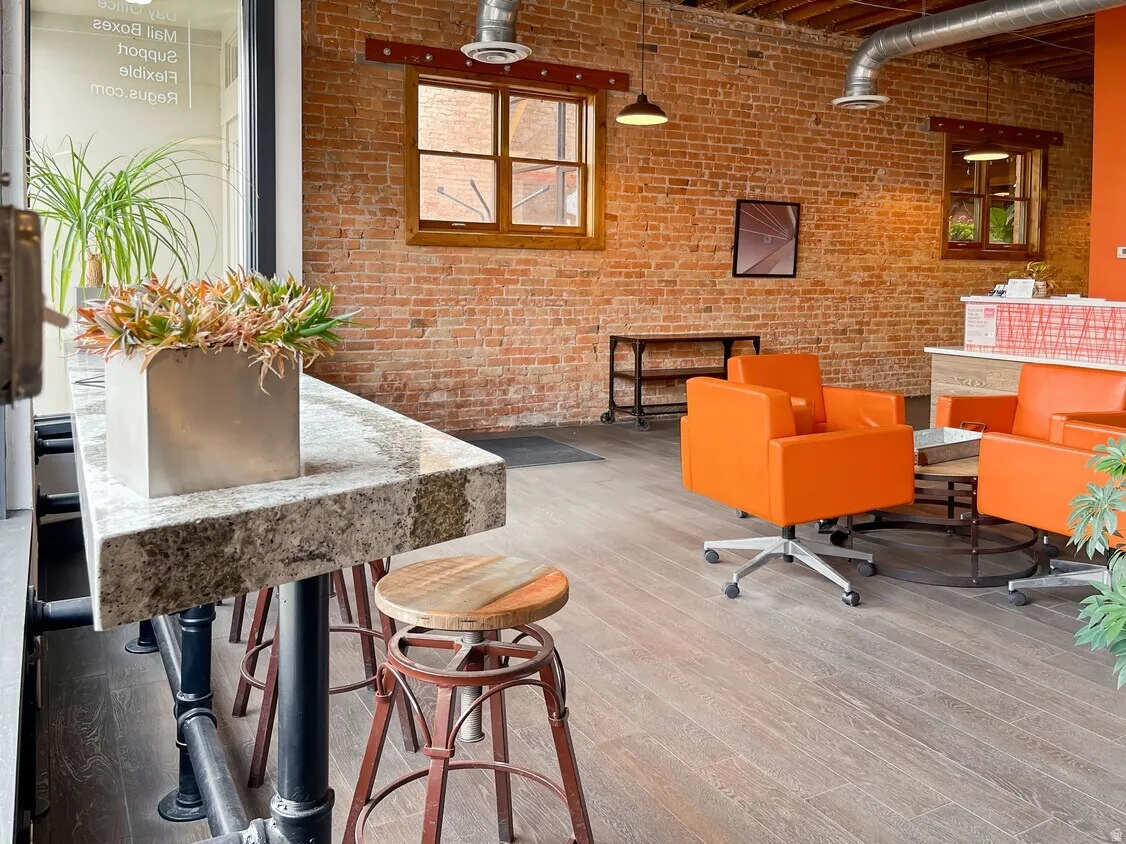 Exposed brick walls, wood-finish flooring, industrial-style ductwork, and exposed ceiling joists