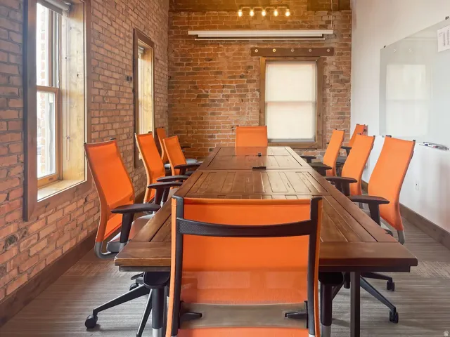 Exposed brick walls, wood-finish flooring, and multiple window openings with wood trim