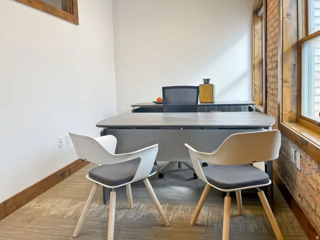 Exposed brick wall, wood-finish window trim, light-toned carpeting, and wood-finish baseboard