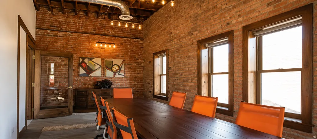 Exposed brick walls, exposed ceiling joists, wood-finish flooring, industrial-style lighting, and wood-framed windows