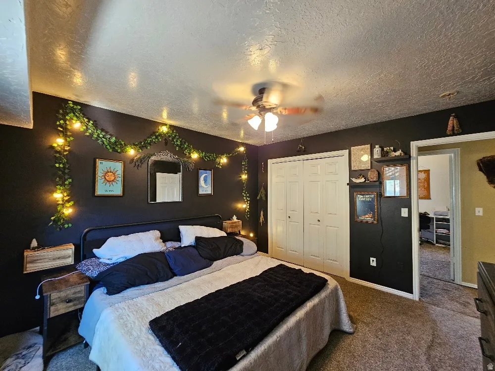 Bedroom featuring a ceiling fan, plush carpeting, and bi-fold closet doors