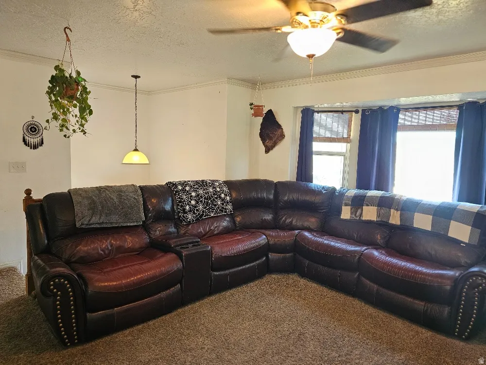 Recessed bay window, ceiling fan with integrated lighting, decorative crown molding, and pendant light fixture