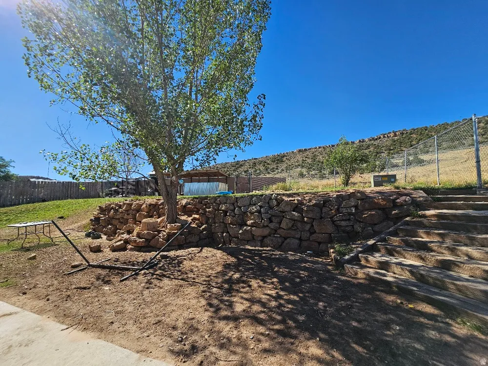 Tiered landscaping featuring a stone retaining wall and integrated steps