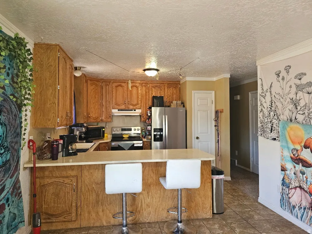 Kitchen featuring wood cabinetry, stainless steel refrigerator, and a built-in breakfast bar