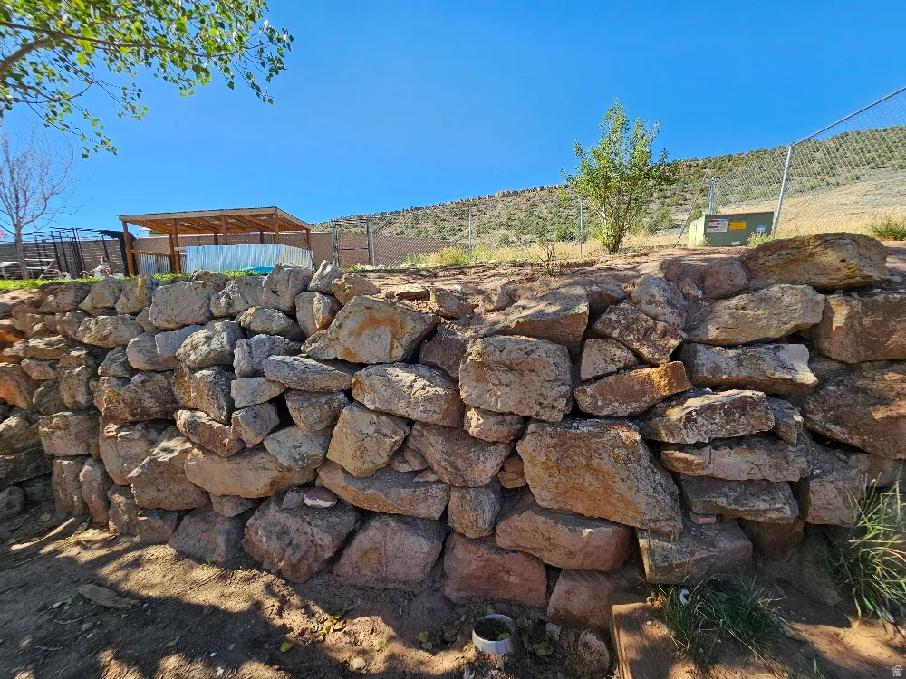 Terraced landscaping featuring a stone retaining wall and a built-in pergola