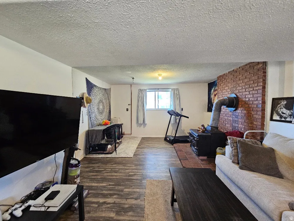 Wood-finish flooring, brick accent wall, a window with natural light, and recessed lighting