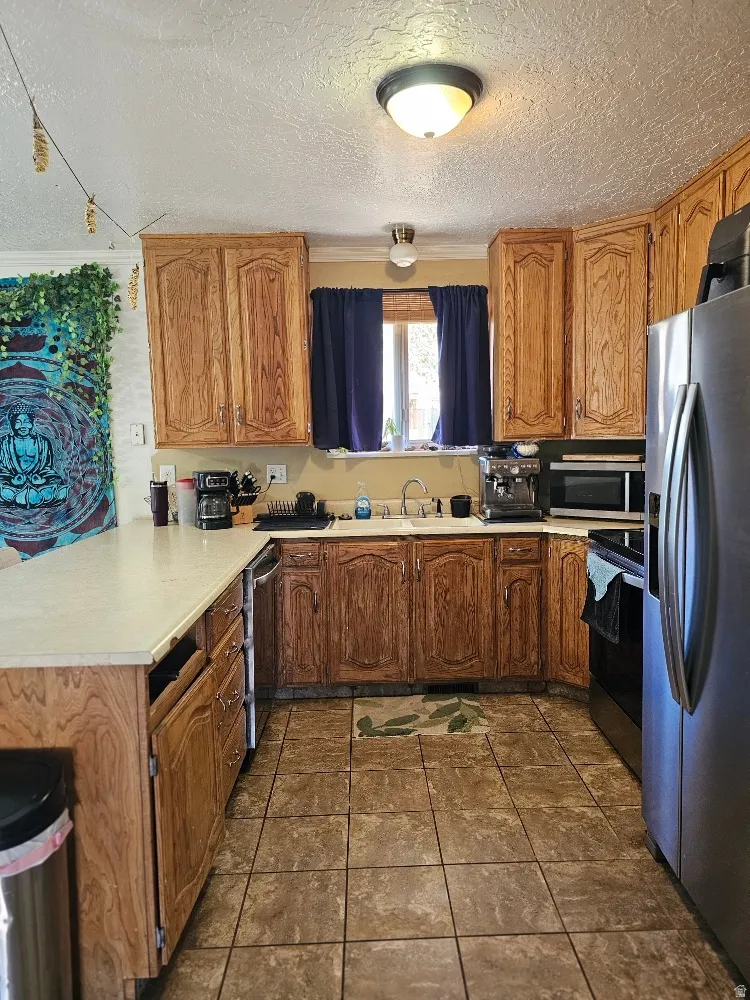 U-shaped kitchen featuring wood cabinetry, light-toned countertops, and tile flooring