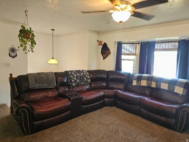 Recessed bay window, ceiling fan with integrated lighting, decorative crown molding, and pendant light fixture