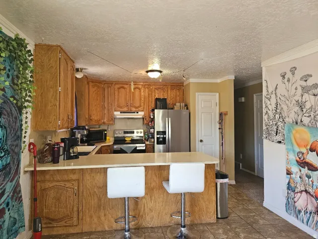 Kitchen featuring wood cabinetry, stainless steel refrigerator, and a built-in breakfast bar