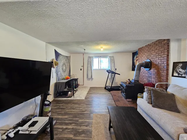 Wood-finish flooring, brick accent wall, a window with natural light, and recessed lighting
